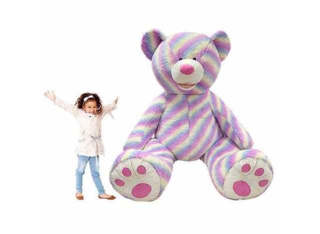 a large rainbow-colored plush bear next to a child
